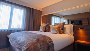 A modern hotel room with a large bed, a flat-screen TV, and a large window with curtains. - The Redhurst Hotel (Glasgow)