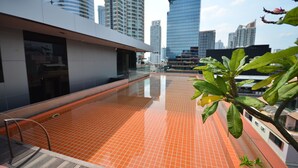 A rooftop pool with orange tiles, surrounded by modern buildings and a clear sky. - The Heritage Hotels Bangkok (Bangkok)
