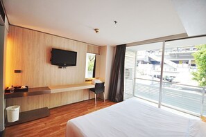 A modern hotel room with a large bed, a desk, a flat-screen TV mounted on the wall, and a large window offering a view of the city. - The Heritage Hotels Bangkok (Bangkok)