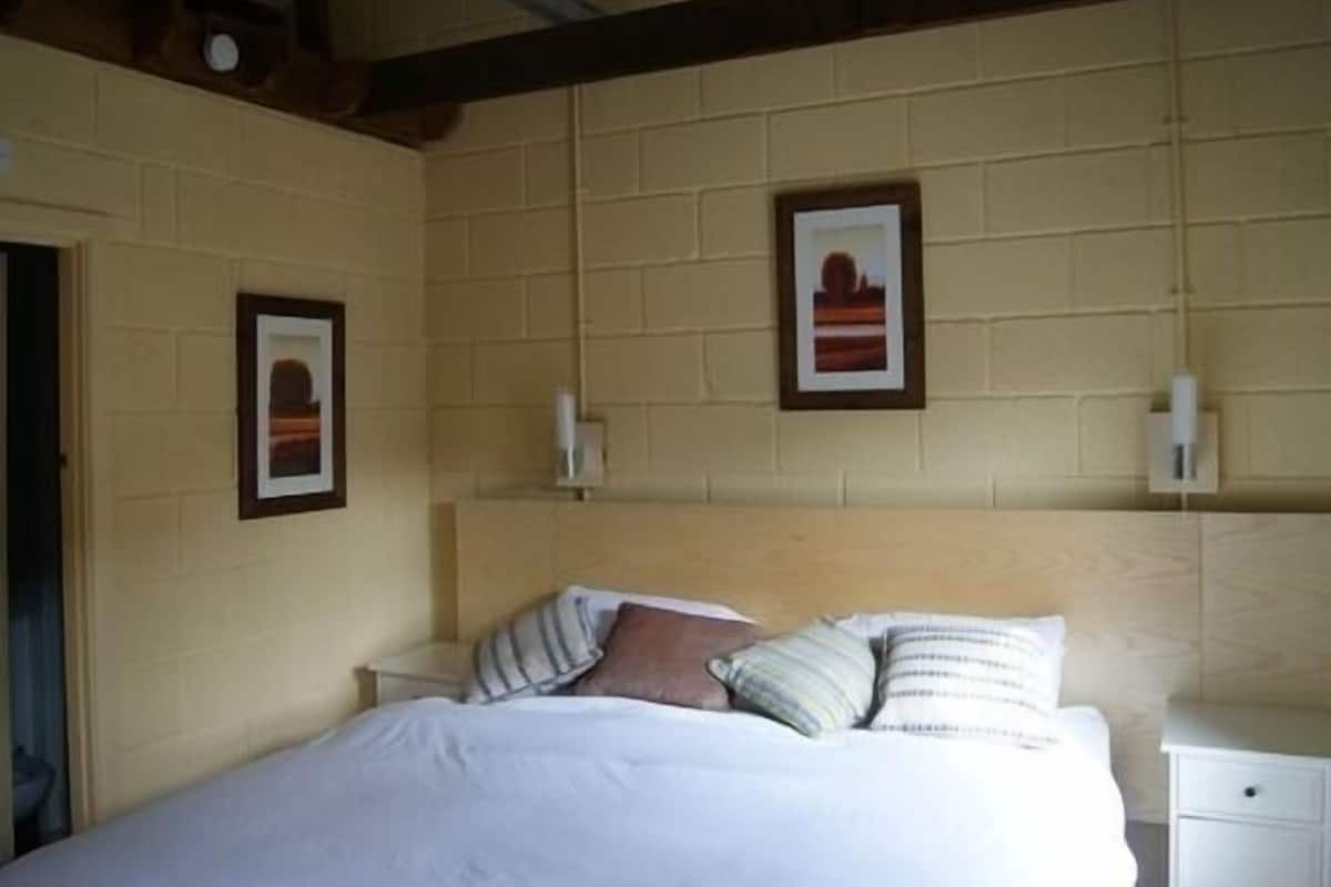 A bedroom with a bed, two bedside tables, and two wall-mounted lamps.