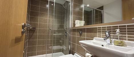 Une salle de bain équipée d’une douche, de toilettes, d’un lavabo et d’un miroir.