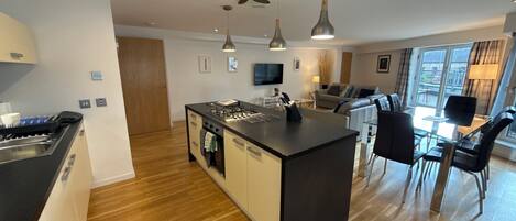 A modern kitchen with a central island, dining area with chairs, and a sofa.