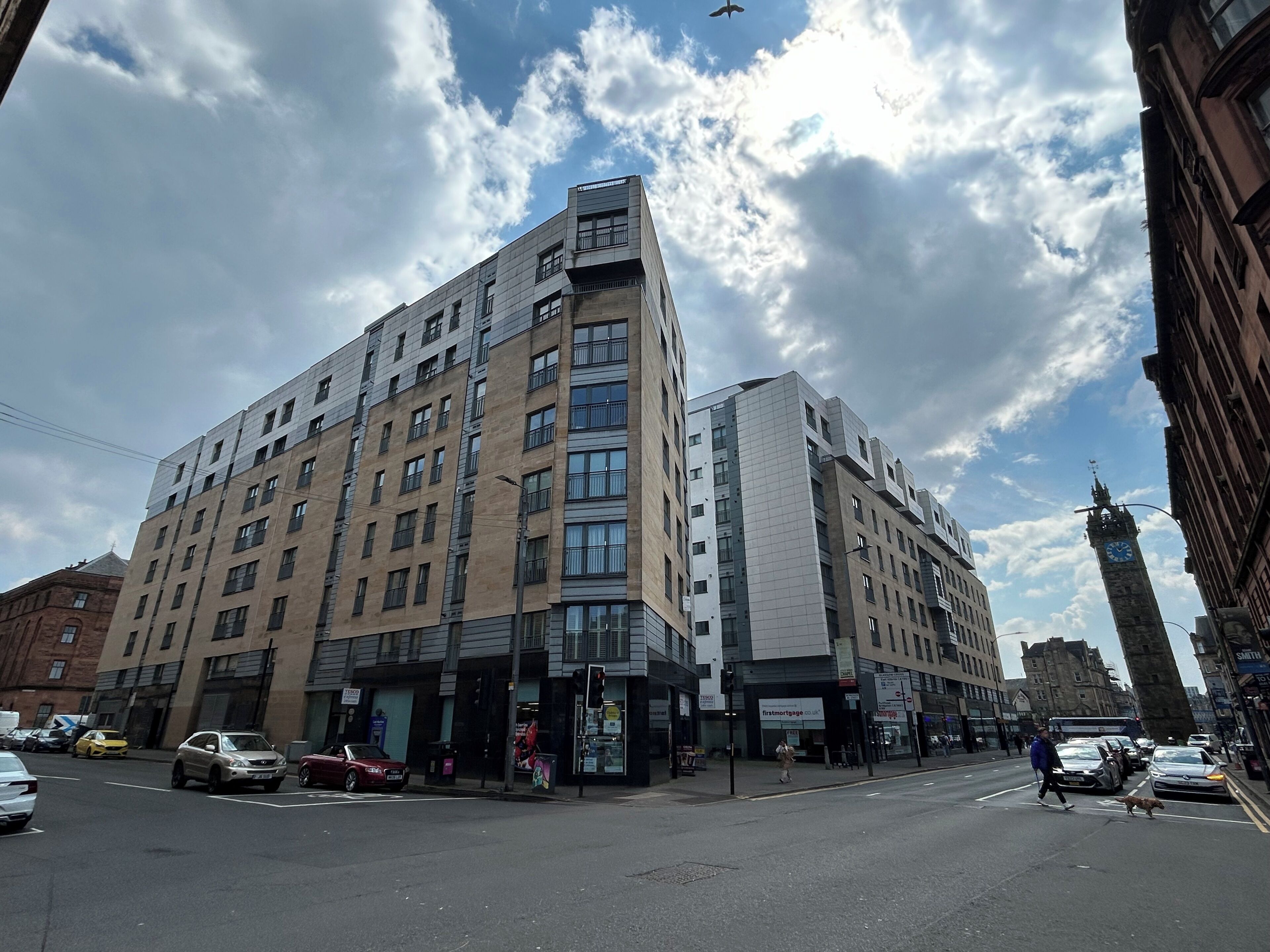 En byggnad med flera våningar och en modern arkitektonisk design, med en kombination av glas- och tegelbeklädda fasader.