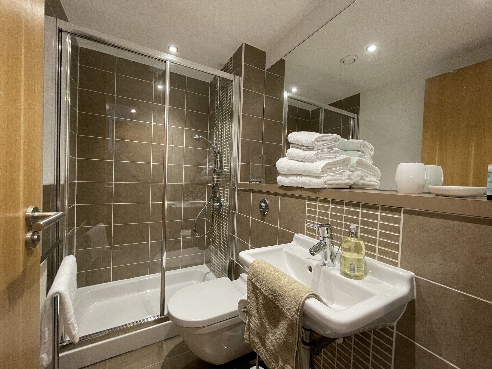 Een moderne badkamer met een glazen douchecabine, een wit toilet en een wastafel met handdoekrek.