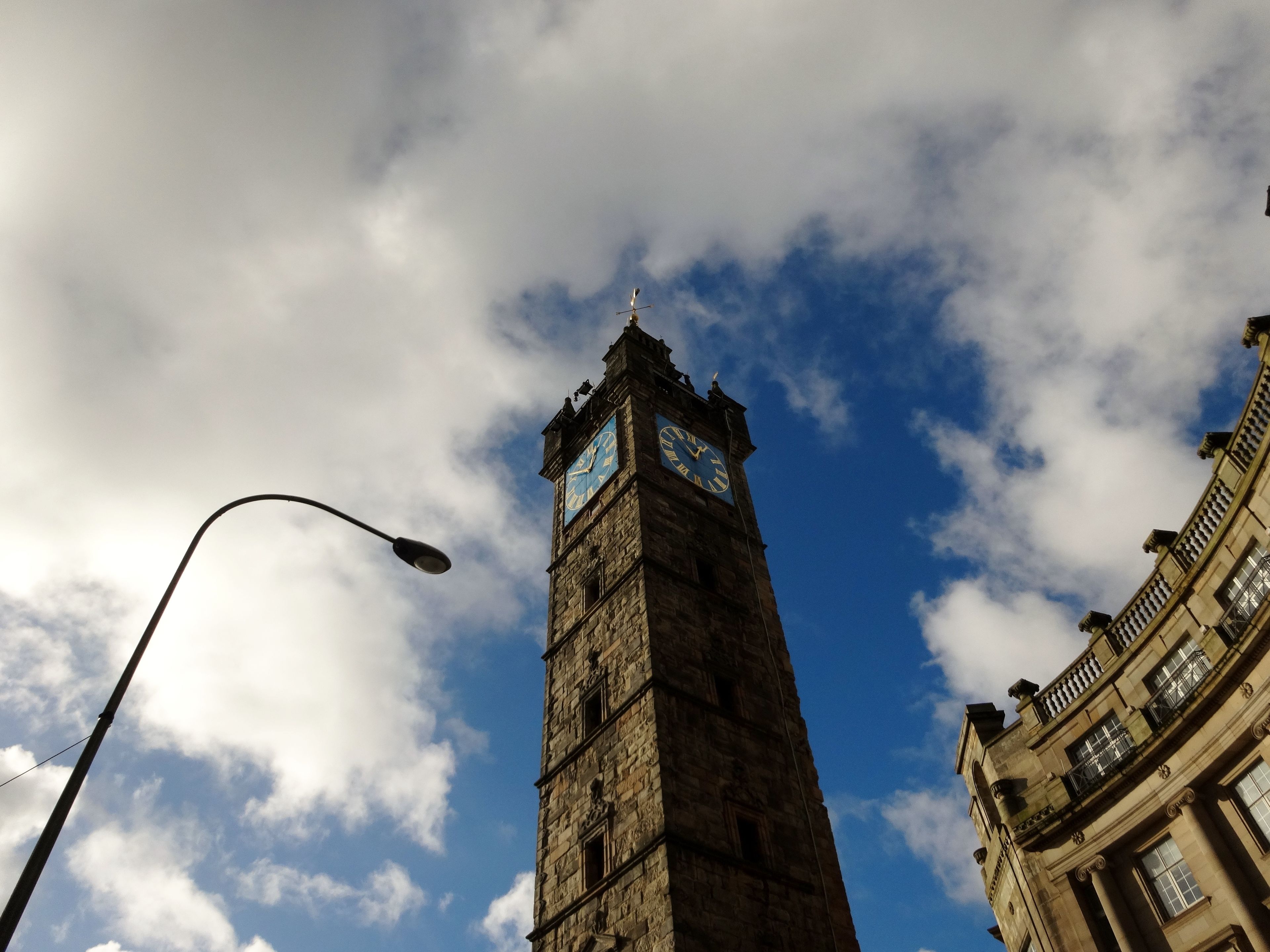Un beffroi historique doté d’une horloge, avec un ciel dégagé et quelques nuages en arrière-plan.