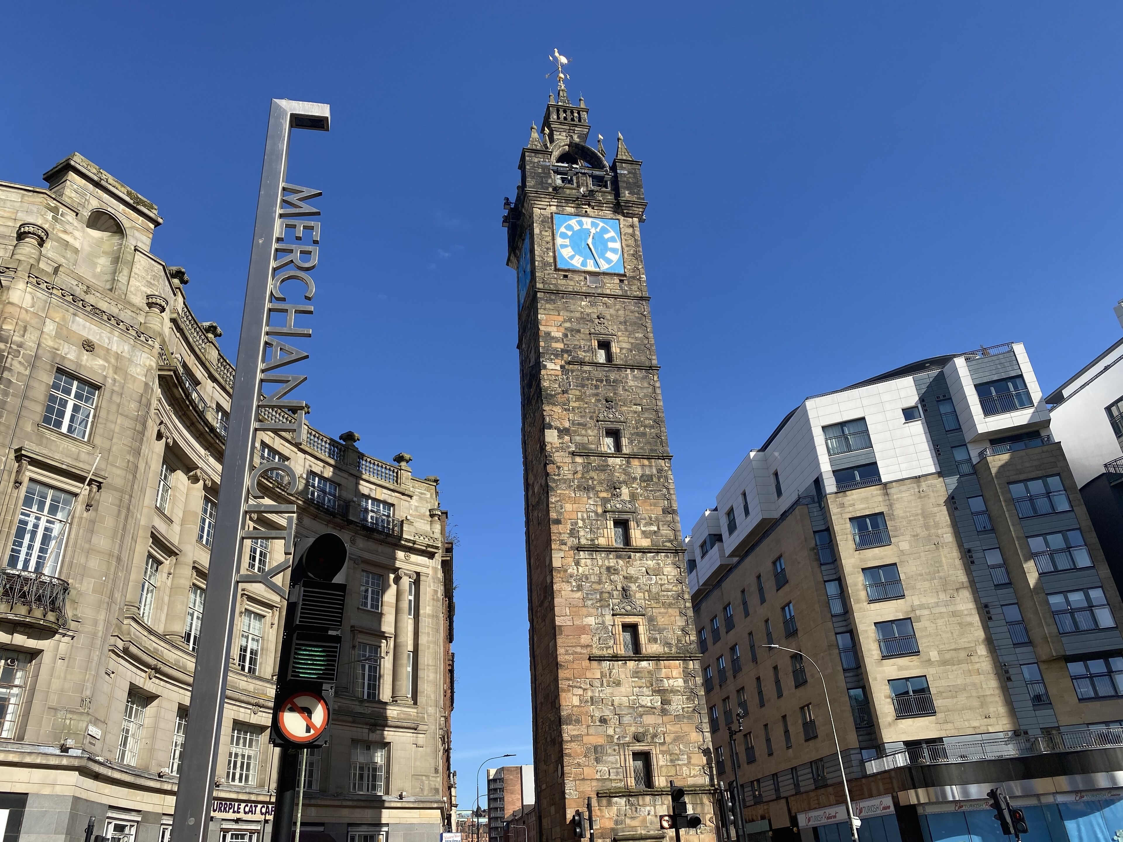 A historic clock tower with a clock face, surrounded by modern buildings.