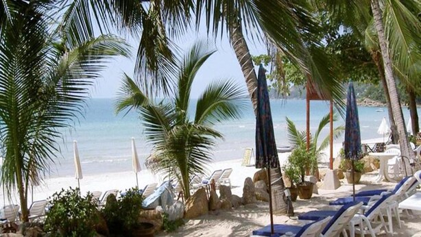 A beachside lounge area with lounge chairs, umbrellas, and potted plants. - Samui Beach Apartments (Koh Samui)