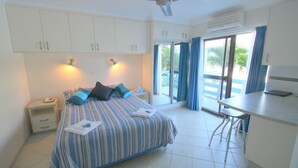 A bedroom with a bed, bedside tables, a desk, and a chair. - Coral Point Lodge (Shute Harbour)