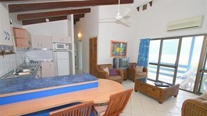 A compact living space with a kitchenette, a dining area, and a seating area with a view. - Coral Point Lodge (Shute Harbour)