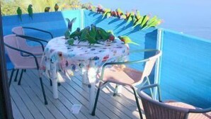 A balcony with a table and chairs, overlooking a body of water and a distant island. - Coral Point Lodge (Shute Harbour)