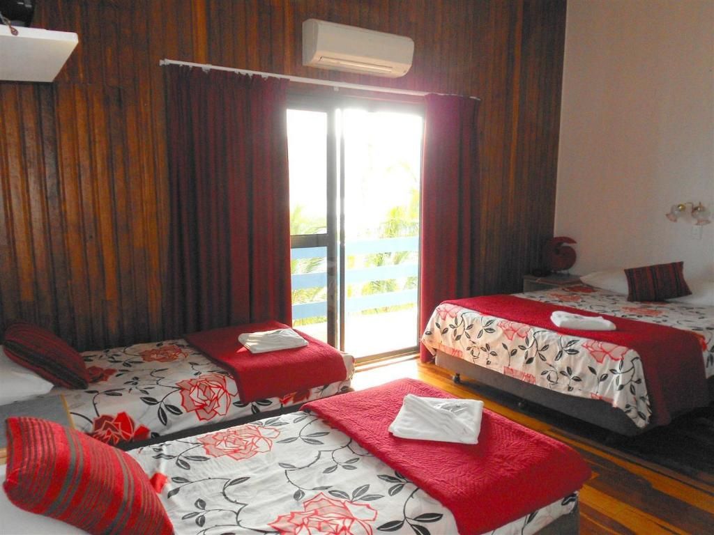 A hotel room with two beds, a sliding glass door to the outside, and a ceiling fan.