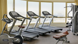 A gym with treadmills, a bench, and weight machines, with large windows offering a city view. - Marriott Executive Apartments Riyadh, Convention Center (Riyadh)