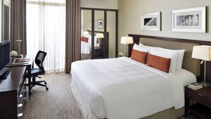 A hotel room with a large bed, a desk with a computer, a chair, and a nightstand with a lamp. - Marriott Executive Apartments Riyadh, Convention Center (Riyadh)