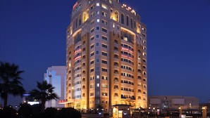 A multi-story hotel with a curved facade, illuminated windows, and signage indicating "Marriott" and "Executive Apartments." - Marriott Executive Apartments Riyadh, Convention Center (Riyadh)