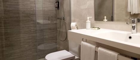 Un baño moderno con cabina de ducha de vidrio, un lavabo blanco y un inodoro.
