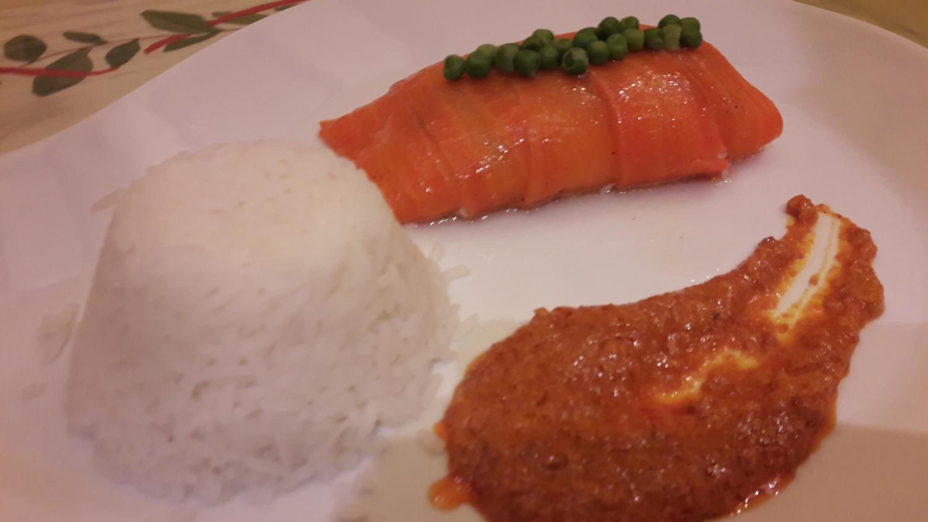 Une assiette contenant du saumon, du riz et un plat à base de tomates.