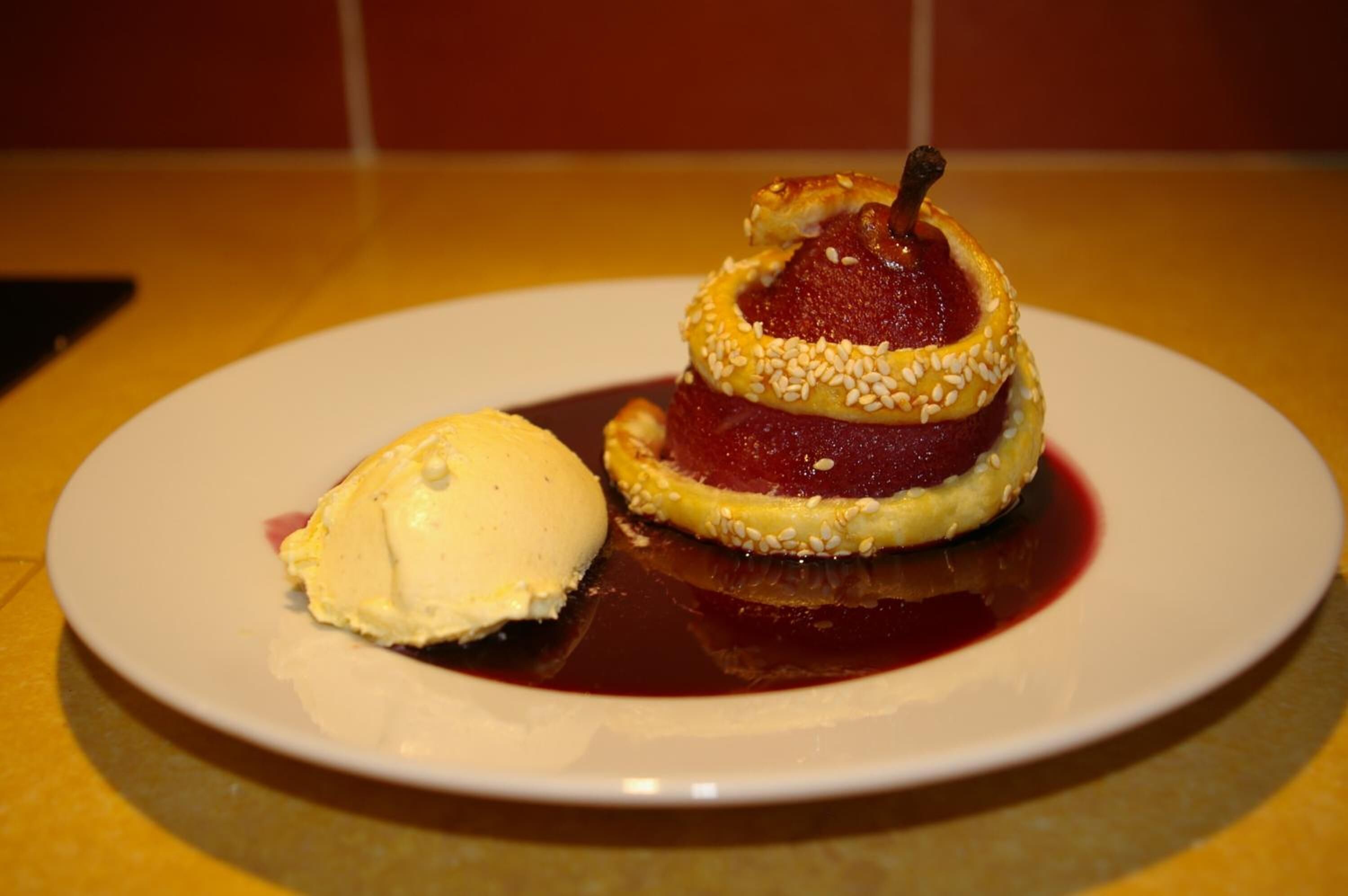 Ein Dessert mit Beerentopping und einer Kugel Eis auf einem weißen Teller.