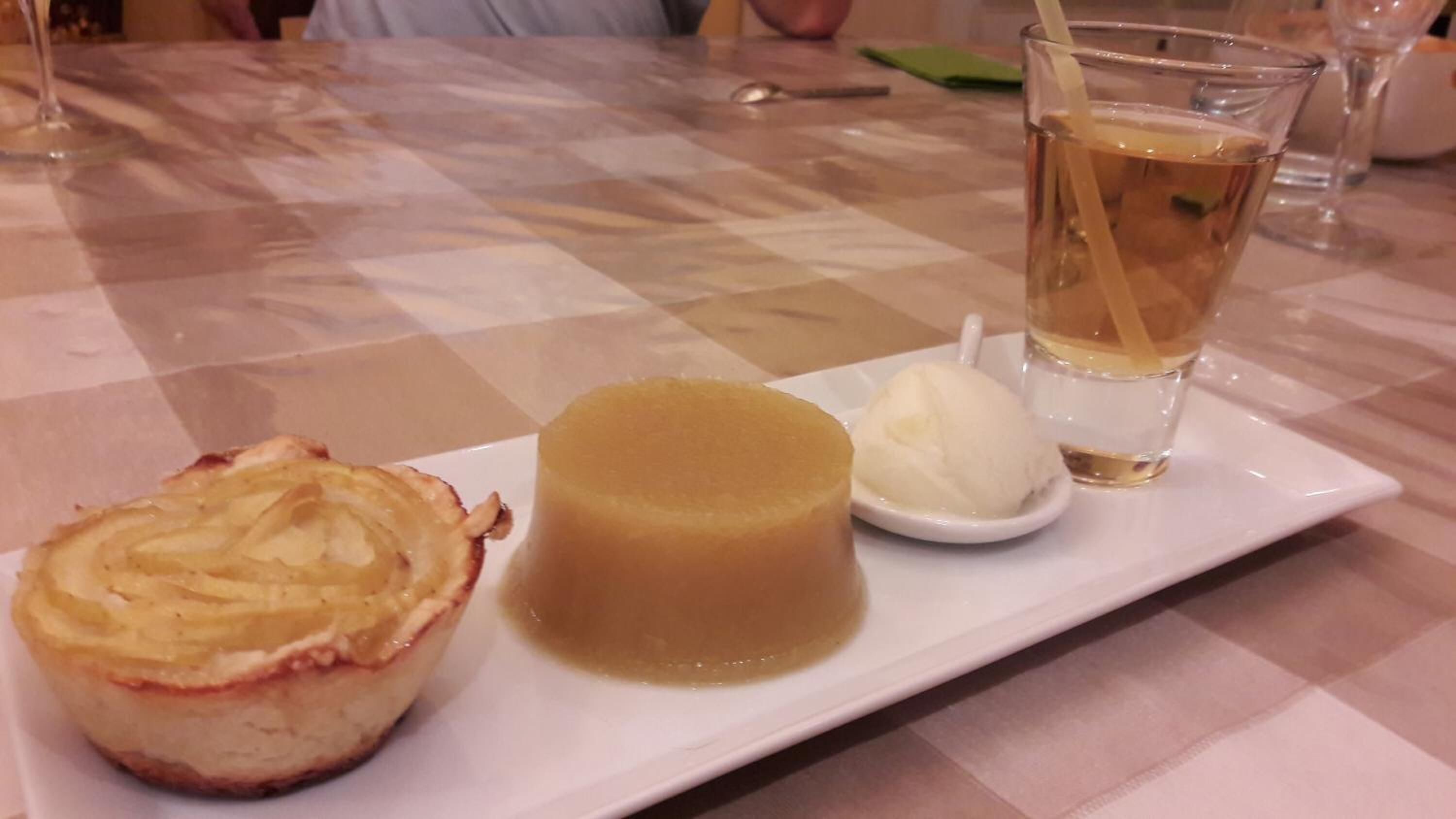 Ein Dessertteller mit Flan, einer Kugel Eis und einem Glas Eistee.