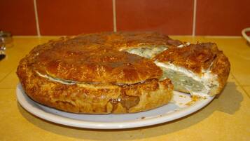 A round, golden-brown pie with a flaky crust, placed on a white plate on a yellow countertop.