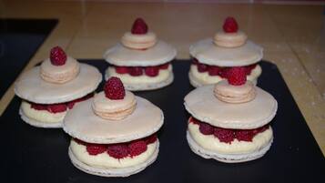 Six dessert items with raspberry and cream layers, arranged on a black surface.