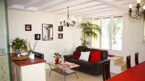 A modern living room with a sofa, coffee table, and a dining area with a red tablecloth. - La Cognee (Cugnaux)