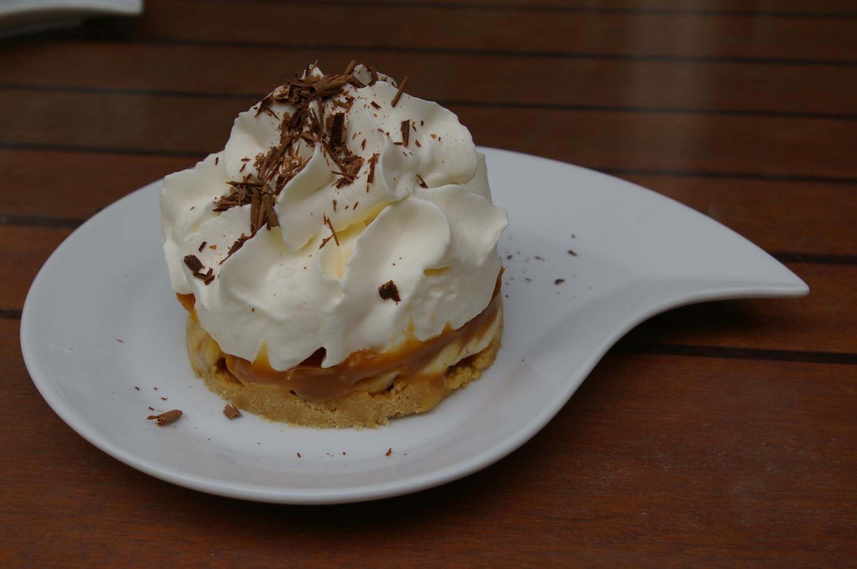 Ein Dessert auf einem weißen Teller mit Schlagsahne und Schokoladenraspeln.