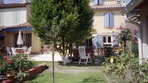 A courtyard with a tree, white chairs, and a table. - La Cognee (Cugnaux)