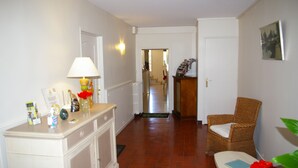 A hallway with a white cabinet, a wicker chair, and a door leading to another room. - La Cognee (Cugnaux)