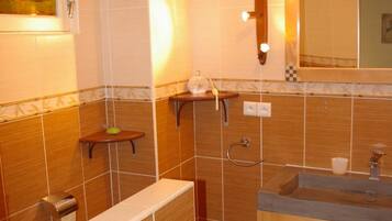 Un baño con lavamanos, espejo, toallero y un pequeño estante con artículos de tocador.
