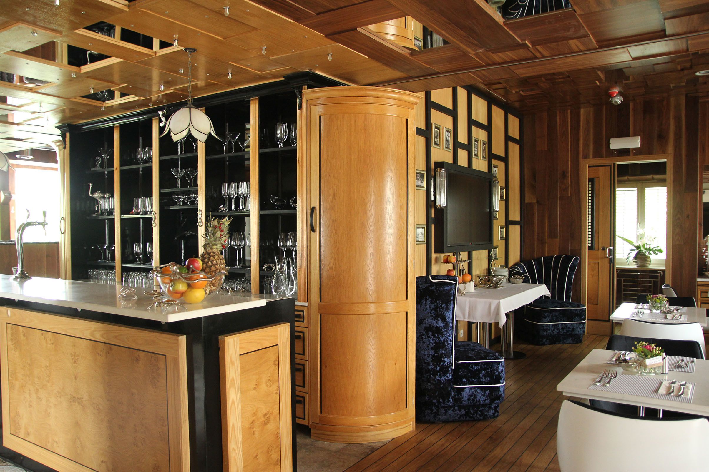Ein Holzinterieur mit Barbereich, Esstischen und einem Fernseher.