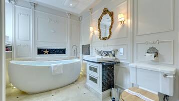 A bathroom with a freestanding bathtub, a sink with a mirror, and a toilet.