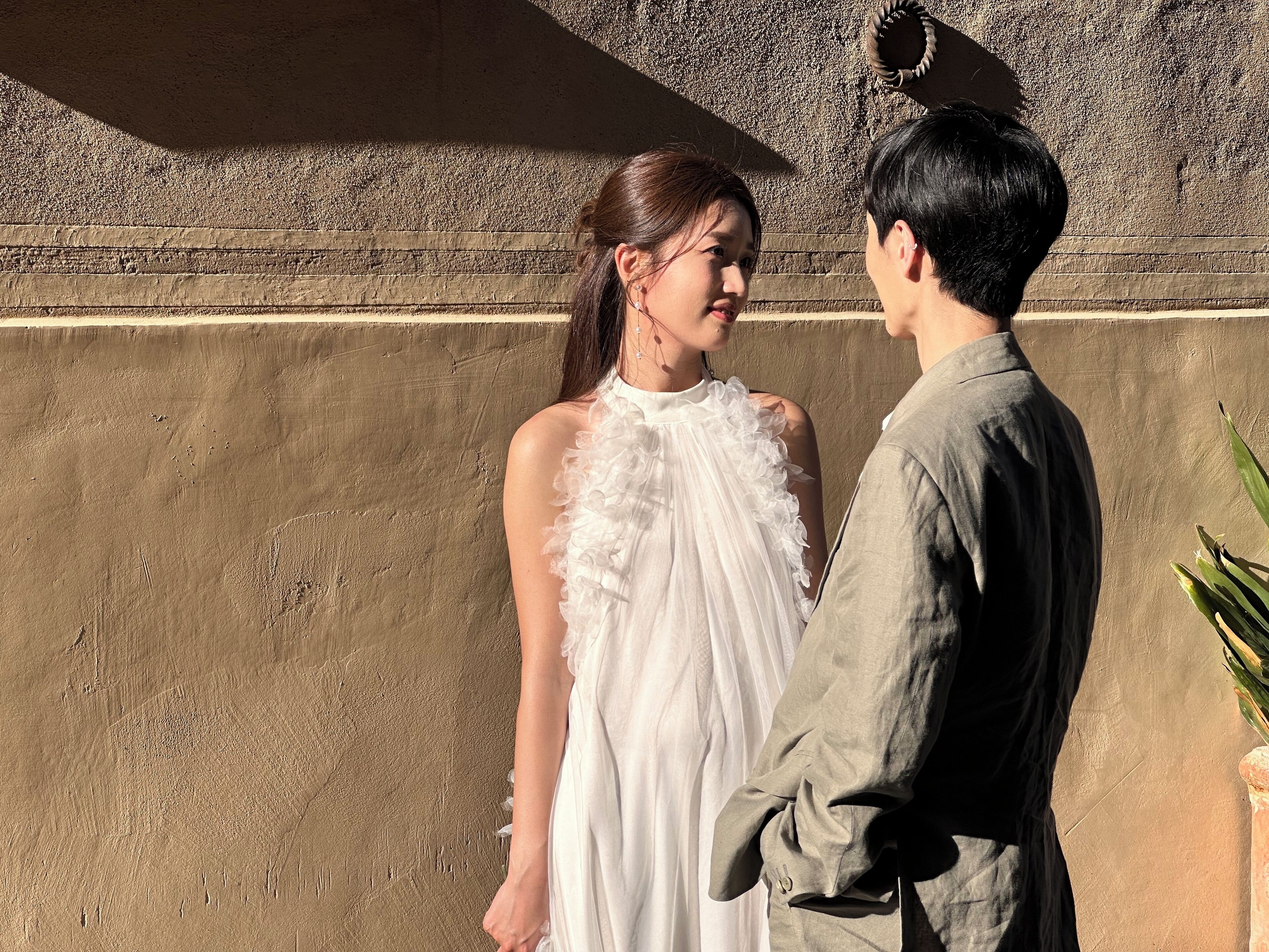 A man and a woman standing in front of a textured wall.