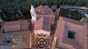 Vista aérea de un edificio histórico con una torre central, diseño de techo simétrico y un patio decorativo.