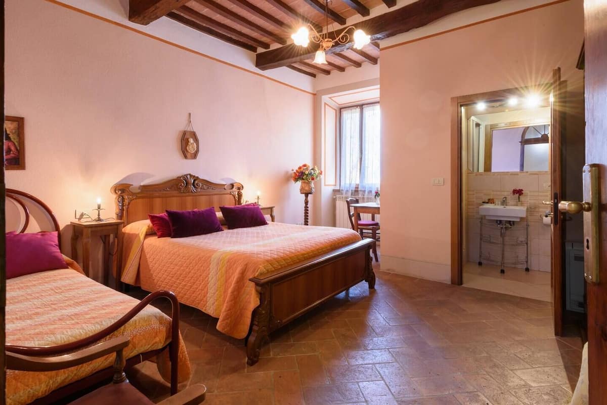 A bedroom with two wooden beds, a wooden dresser, and a small table with a lamp.