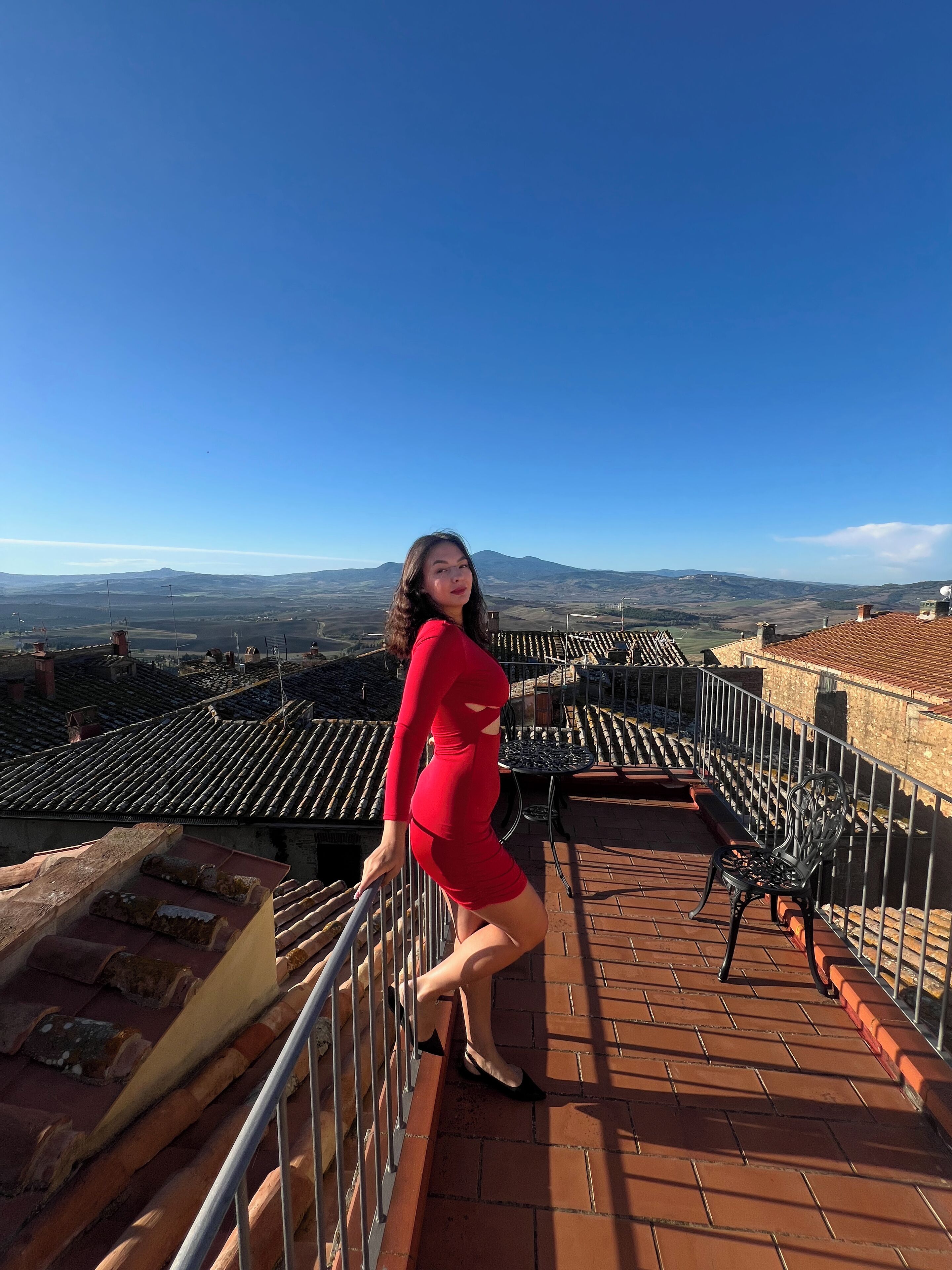 Une terrasse dotée d’un sol carrelé et de rampes en métal, offrant une vue sur un paysage montagneux.