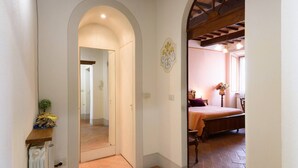 Un pasillo con un arco que da a un dormitorio con cama y cómoda.