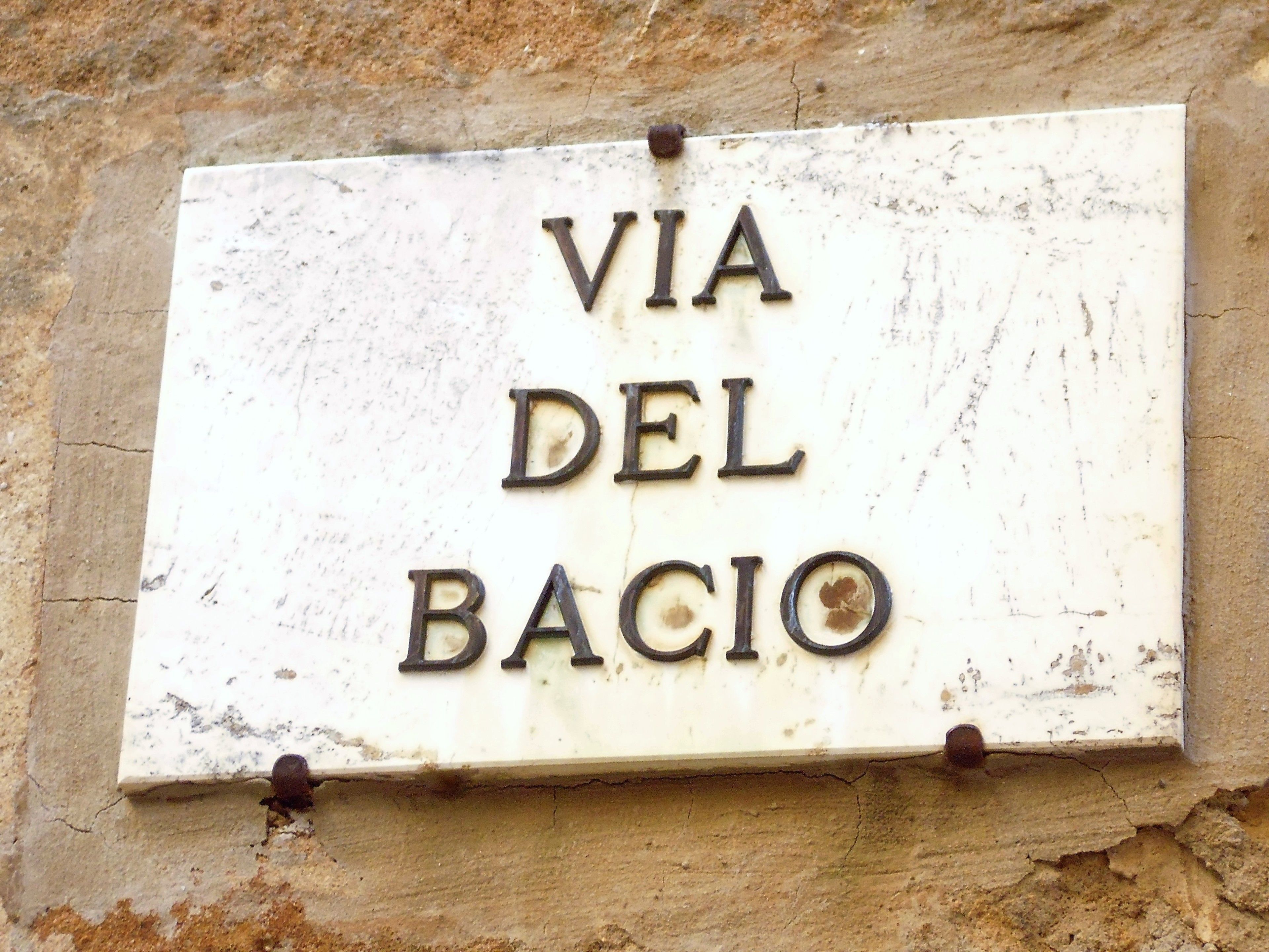 A sign with the text "VIA DEL BACIO" mounted on a wall.
