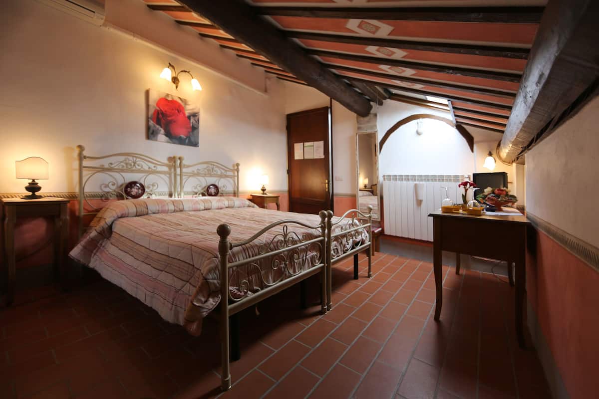 A bedroom with a bed, bedside tables, a desk, and a chair.