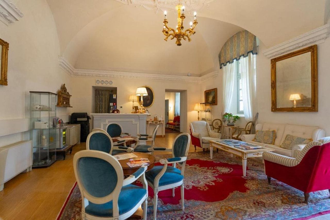 Un salon spacieux comprenant un coin repas, un lustre et un grand miroir.