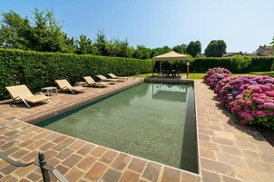 Una piscina al aire libre, sillones reclinables de piscina