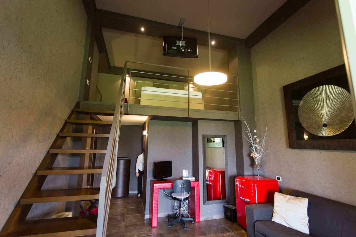 A modern interior with a staircase, a desk with a computer, a sofa, and a red cabinet.