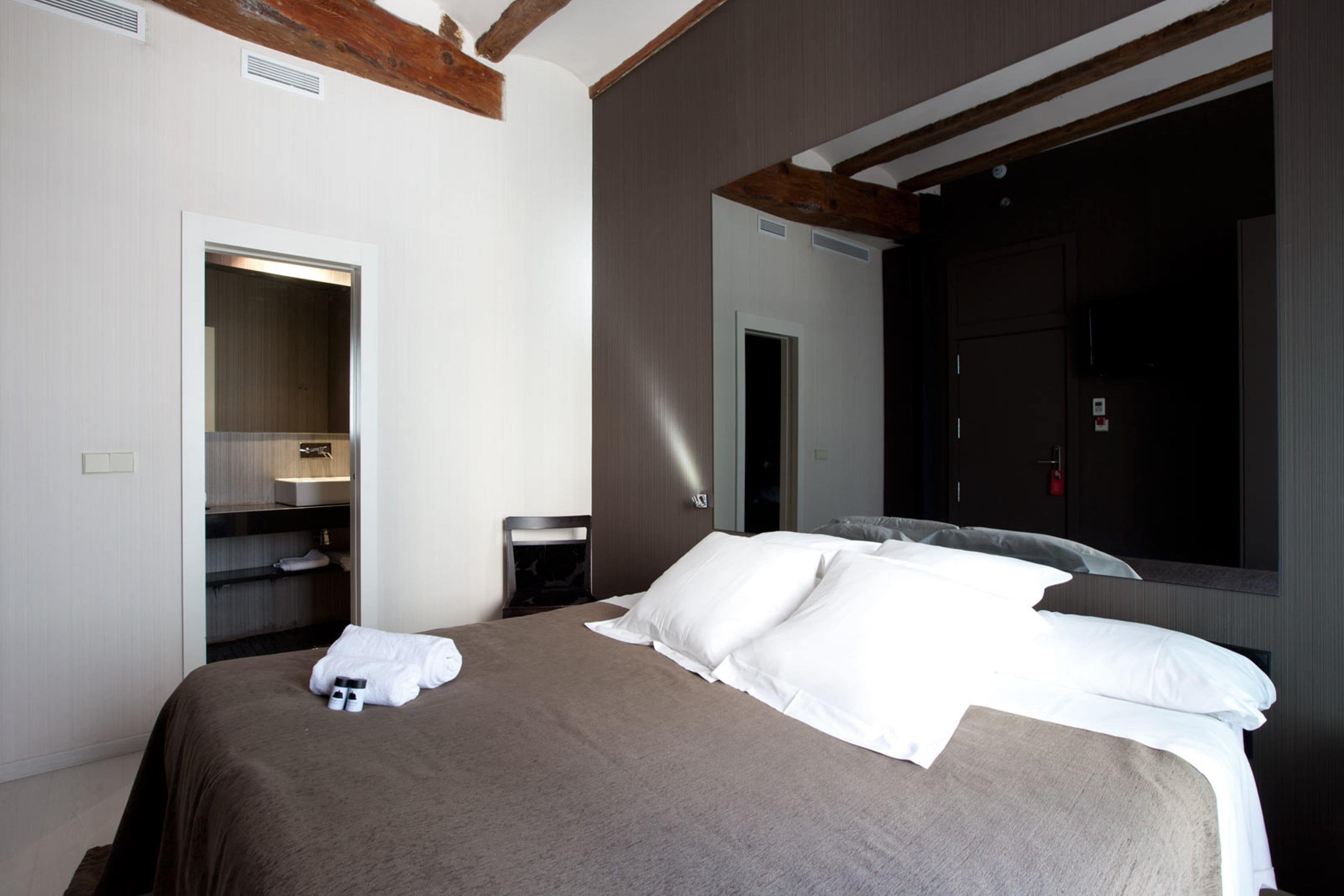 Une chambre d’hôtel moderne avec un grand lit, une armoire et un miroir.