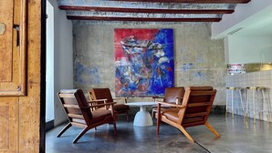 A modern interior with a concrete wall, a large abstract painting, and a seating area with two leather chairs and a small table. - Cosy Rooms Bolsería (Valencia)