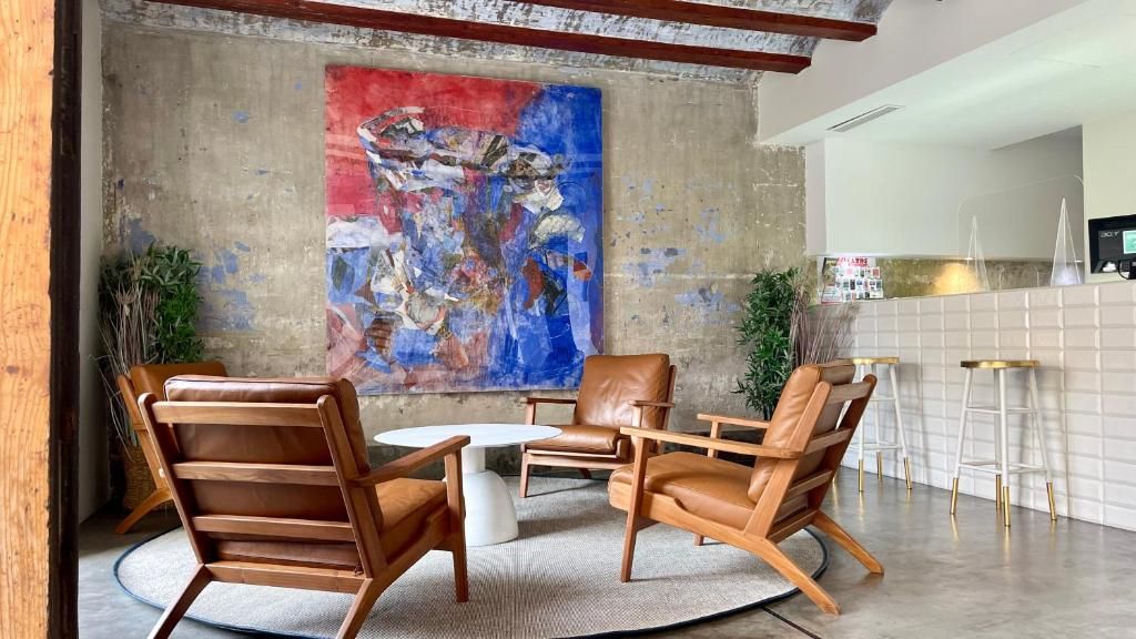 A modern lounge area with leather chairs, a round table, and a large abstract painting on the wall.