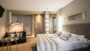 A modern hotel room with a large bed, a sofa, a small round table, and a mirror on the wall. - Cosy Rooms Bolsería (Valencia)