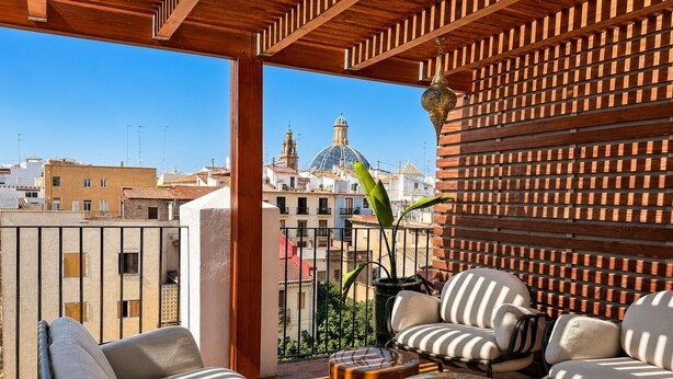 A balcony with a view of a cityscape, including a prominent dome. There are two sofas and a small round table. - Cosy Rooms Bolsería (Valencia)