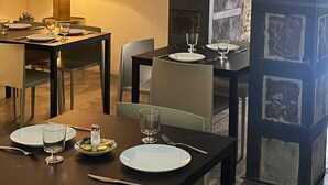A dining area with two tables, each set with plates, glasses, and cutlery. There are framed pictures on the wall, a lamp on the left table, and a wooden door with a rustic design on the right. - Cosy Rooms Bolsería (Valencia)