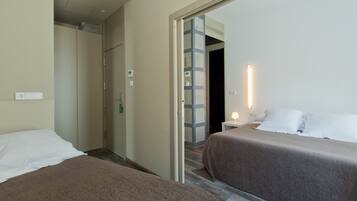 Habitación de hotel con dos camas, un baño y un pasillo que conduce a otra habitación.