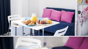 A breakfast setup with croissants, fruit, and orange juice on a table, and a blue couch in the background. - Casamediterranea (Itri)