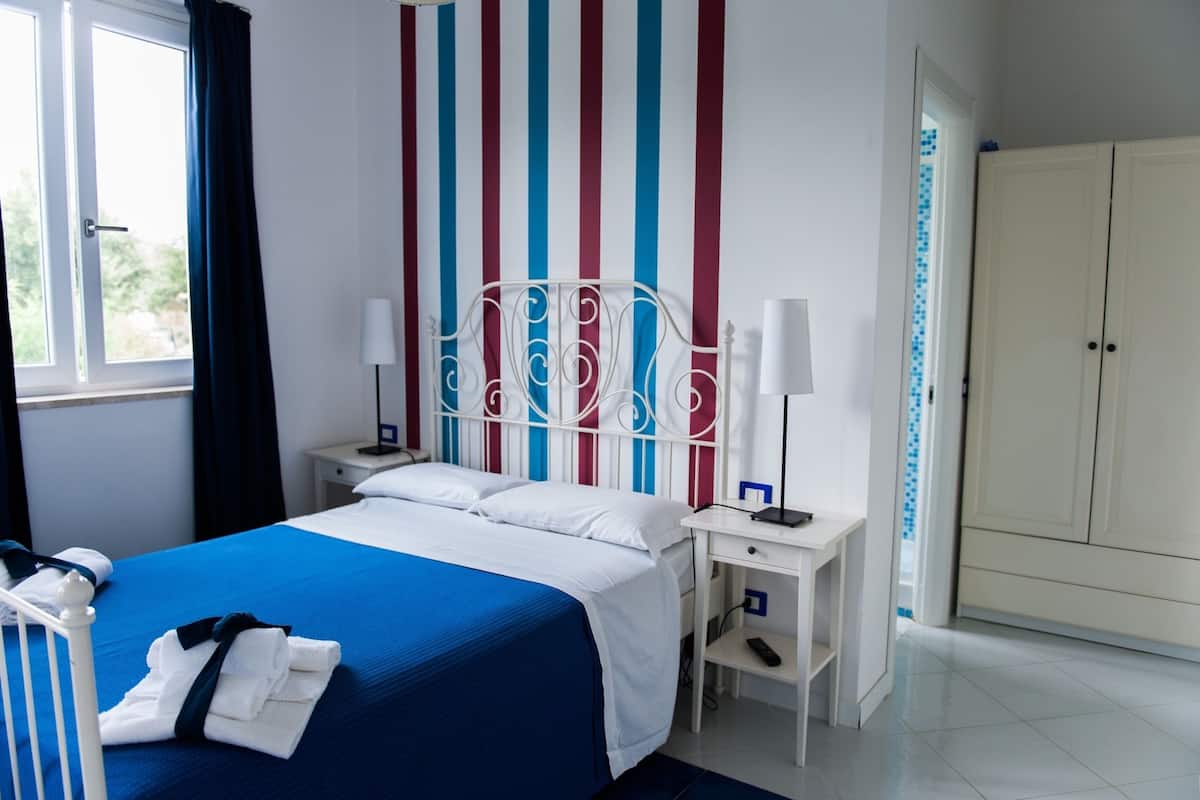A hotel room with a bed, nightstands, a wardrobe, and a striped wall.